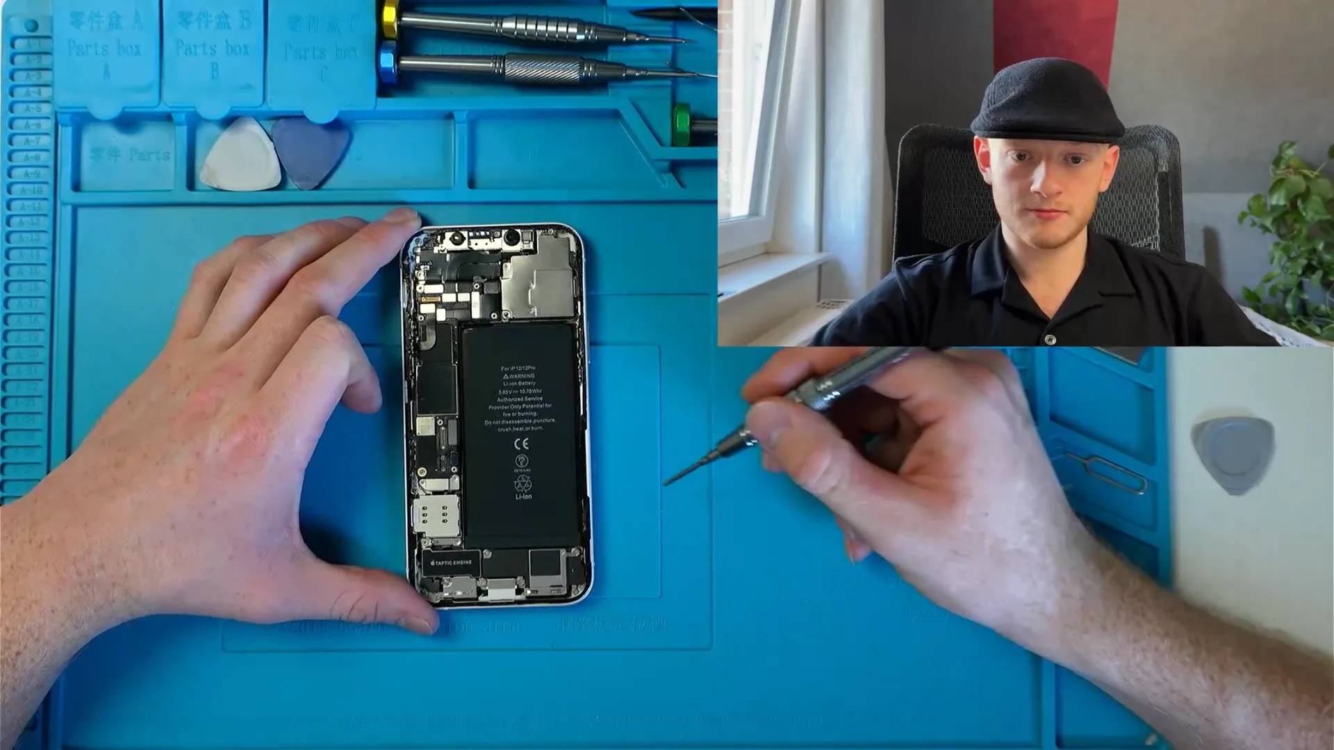 Andrej beim Reparieren eines Handys im Stream, mit Nahaufnahme des geöffneten Geräts.